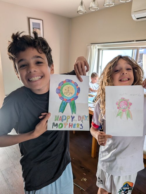 Amichai and Eitan holding up early Mother's Day cards